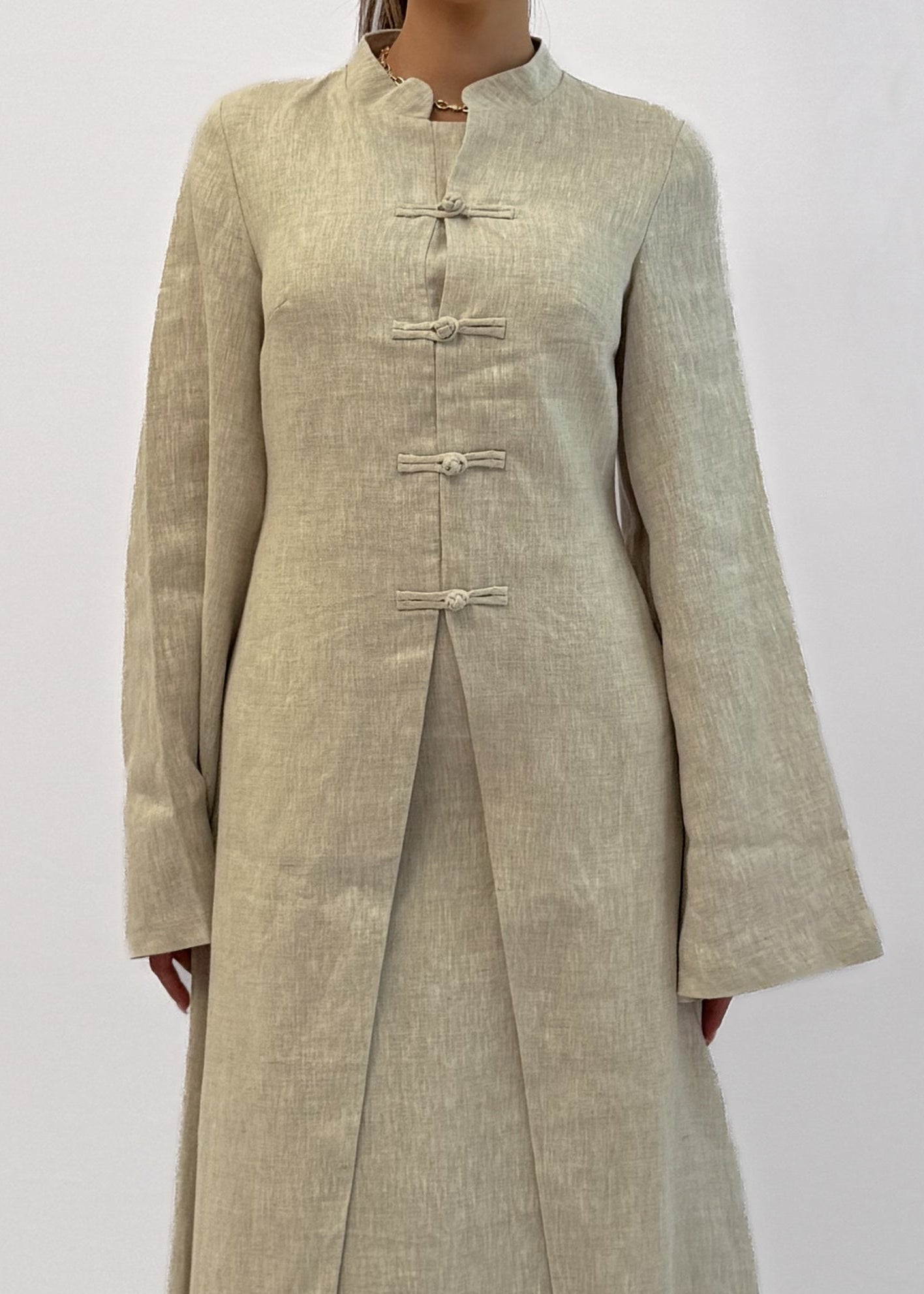 Woman wearing a long beige dress against a white background