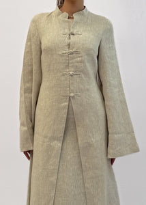 Woman wearing a long beige dress against a white background